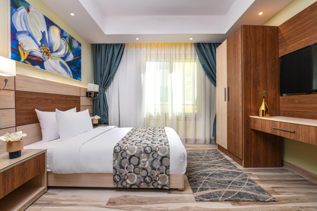 Tolip Resort El Galala Majestic Ain Suchna Exterior foto The photo shows a well-designed hotel room. It features a comfortable bed with a decorative bedspread and two pillows. There are soft curtains framing a window that lets in natural light. On one side, there is a colorful piece of artwork hanging on t