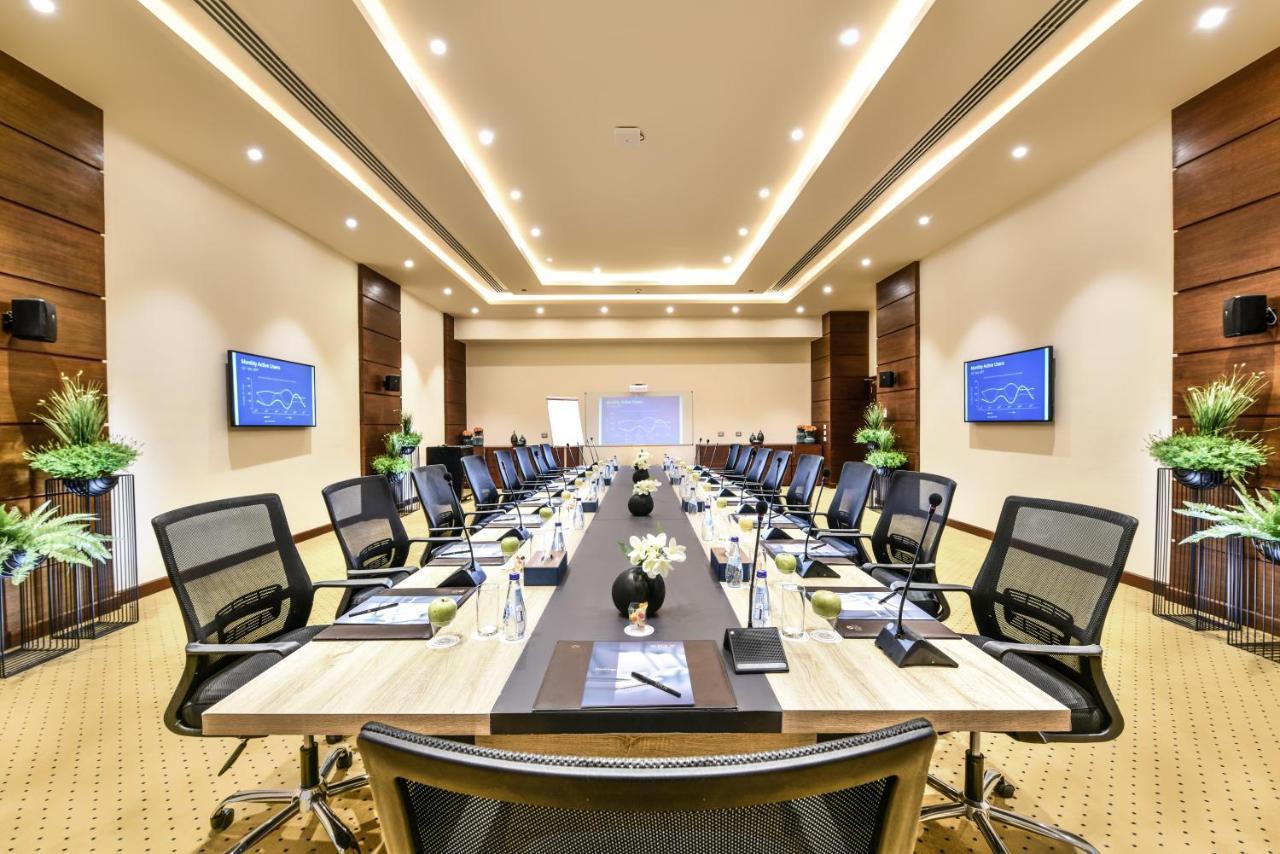 Tolip Resort El Galala Majestic Ain Suchna Exterior foto The photo shows a modern conference room designed for meetings. It features a long rectangular table at the center, surrounded by ergonomic black chairs. The room is well-lit with ceiling lights and has a neutral color scheme. There are two large scr