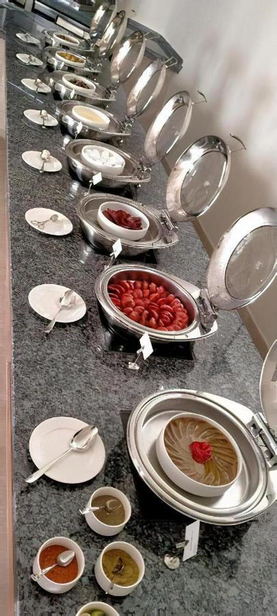 Tolip Resort El Galala Majestic Ain Suchna Exterior foto The photo shows a buffet setup featuring multiple metal serving trays on a dark granite countertop. One tray contains circular slices of food, possibly sausages or a similar dish, while another bowl holds what appears to be red food items, though it'