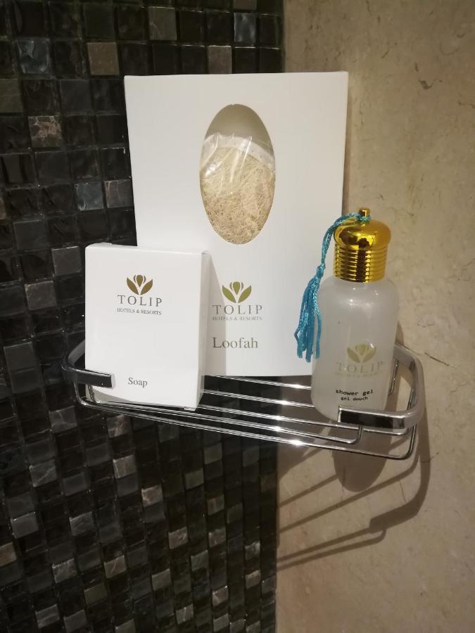 Tolip Resort El Galala Majestic Ain Suchna Exterior foto The photo shows a small metal shelf containing three items related to personal care. 

1. **Soap**: A white box labeled "TOLIP" with the word "Soap" visible on the front.
2. **Loofah**: A package with the same "TOLIP" branding, containing loofah.
3. 
